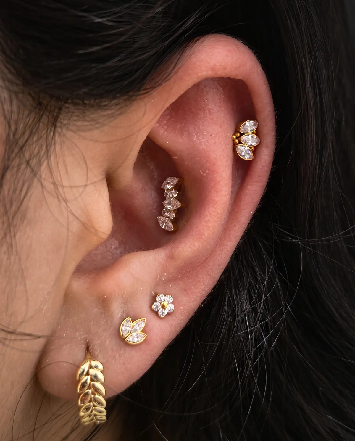 Altın tonlu takılarla tamamlanan minimal ear curation görünümü
